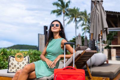 happy-caucasian-pretty-long-hair-elegant-tourist-woman-dress-with-red-suitcase-outside-hotel_11zon-1-scaled.jpg